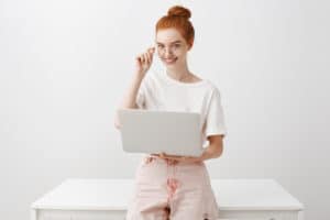 Redhead smiling and holding a laptop