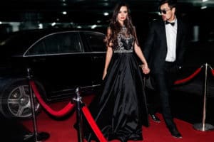 Glamorous young couple walking up the red carpet in formal evening wear